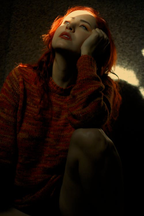 Low Angle Shot of a Woman with Red Hair Wearing Knitted Sweater while Looking Afar