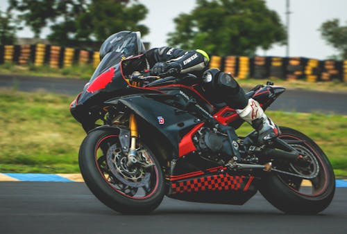 黒と赤のスポーツバイクに乗る黒のアルパインスターレーシングスーツを持つ男