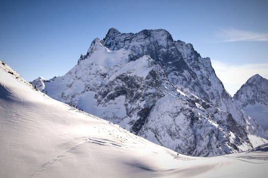 Breathtaking view of snow-covered Dombai mountains under a clear blue sky, perfect for winter adventure.