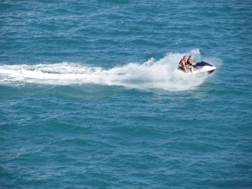 Free A couple riding a jetski on the ocean, creating splashes of water under the bright summer sun. Stock Photo
