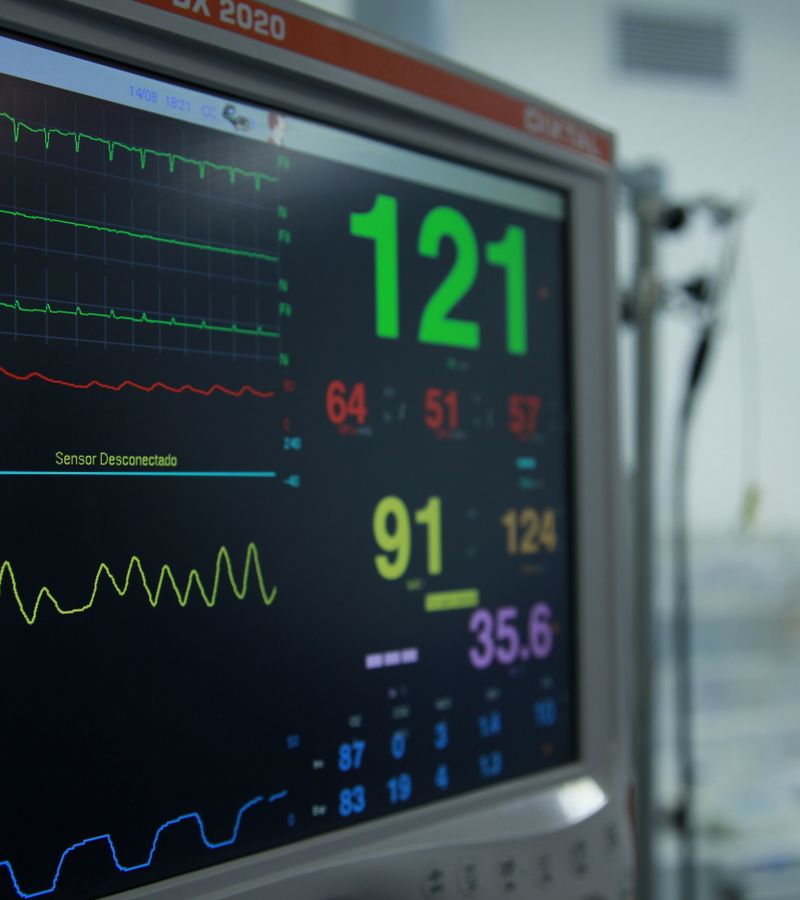 Close-up view of a vital signs monitor showing various medical readings in a hospital setting.