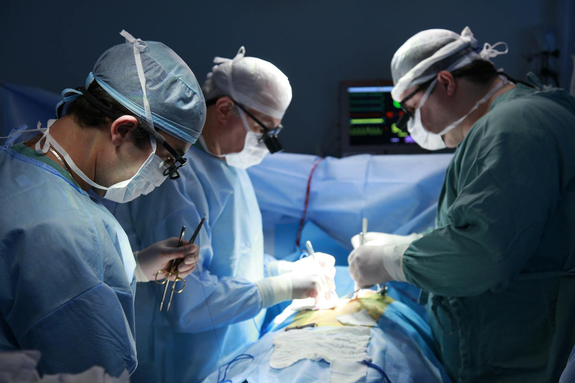 Surgeons in an operating room performing a complex medical procedure under bright lights.