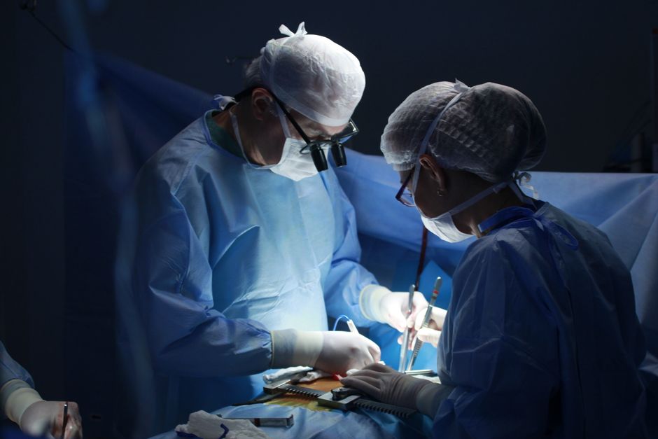 手術室で保護具を着用し、複雑な手術を行う外科医。