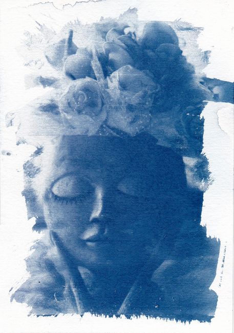 Cyanotype image of a serene doll with closed eyes and floral headpiece in blue tones.