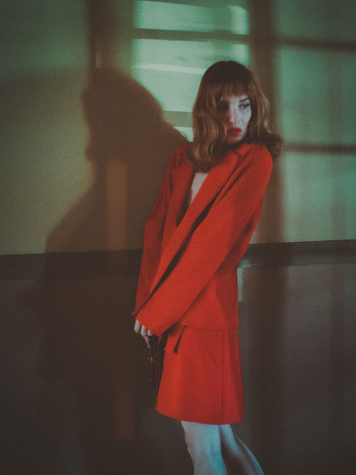 A woman in a red blazer and skirt looking over her shoulder — red as power dressing