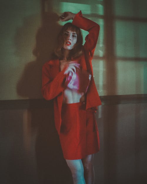 A Woman in Red Long Sleeves and Skirt Leaning on the Wall with Her Hand on Her Head