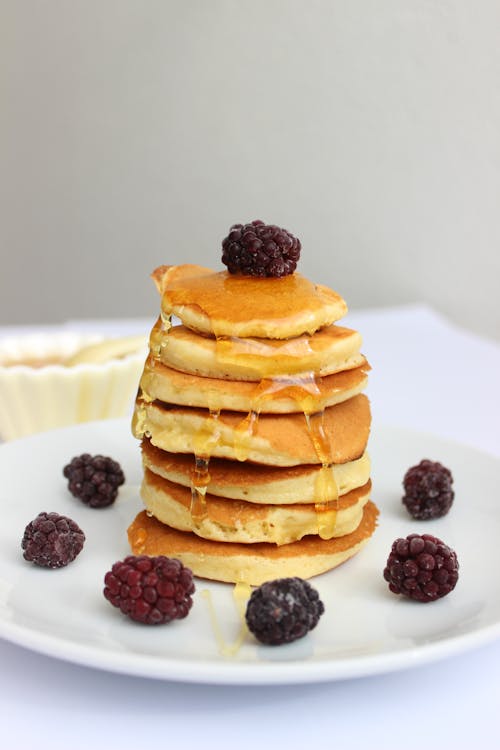 Pancakes With Blackberries and Honey on White Plate