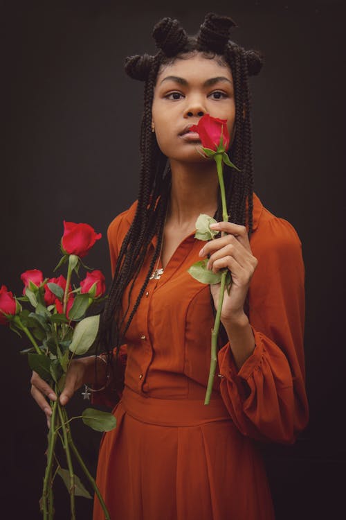 A Woman in Orange Dress Holding a Red Roses