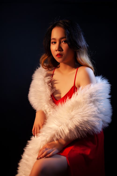A Woman in Red Dress and White Fur Coat Looking with a Serious Face