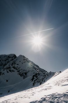 A breathtaking view of snow-covered mountain peaks under a bright sun, casting dramatic shadows.