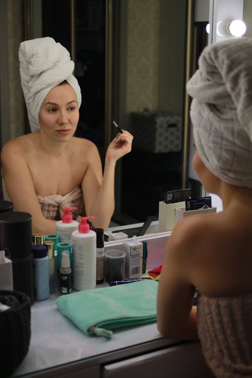 Free Photo of a Woman with a Head Towel Putting on Makeup Stock Photo