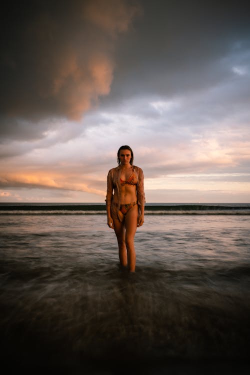Free Woman in Bikini Walking in the Sea at Sunset  Stock Photo