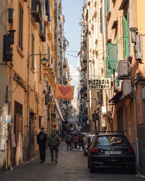 Free Vibrant street scene in Naples with buildings, cars, and pedestrians. Stock Photo