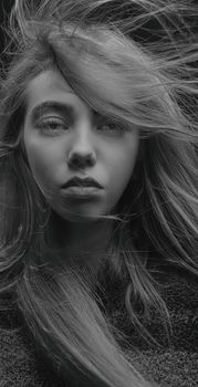Striking monochrome portrait of a woman with windswept hair conveying intensity.
