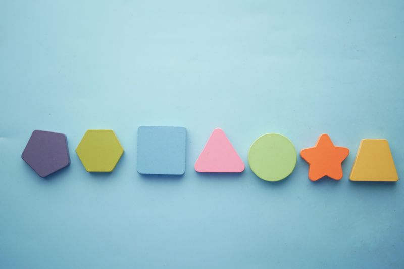 Vibrant geometric shapes arranged in a line on a blue background, perfect for educational themes.
