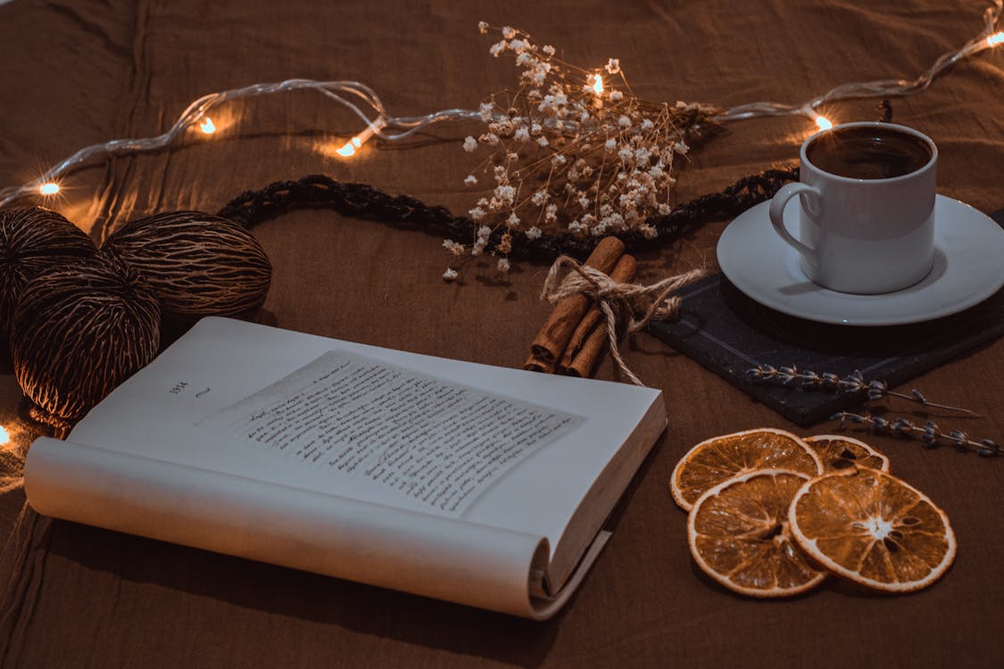 Orange Slices, Lights and Coffee near Open Book · Free Stock Photo