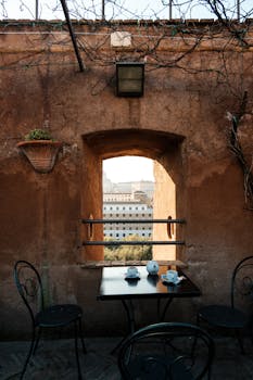 Cozy café table with stunning view of Roman architecture through rustic window.