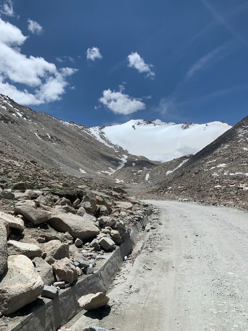 Free Scenic view of rocky path leading through mountainous terrain with snow-capped peaks and blue sky. Stock Photo