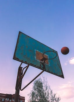 A rustic basketball hoop captured during a sunset, against a clear evening sky, evoking nostalgia.