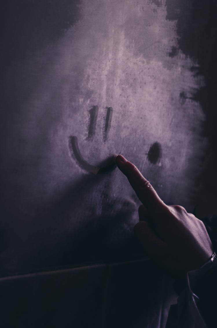 Hand Drawing A Smiley Face On A Dusty Glass 