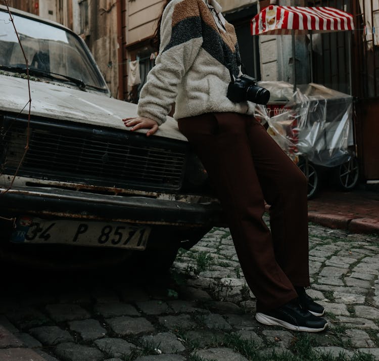 Person Wearing Fleece Sweater And Brown Pants Leaning On A Car