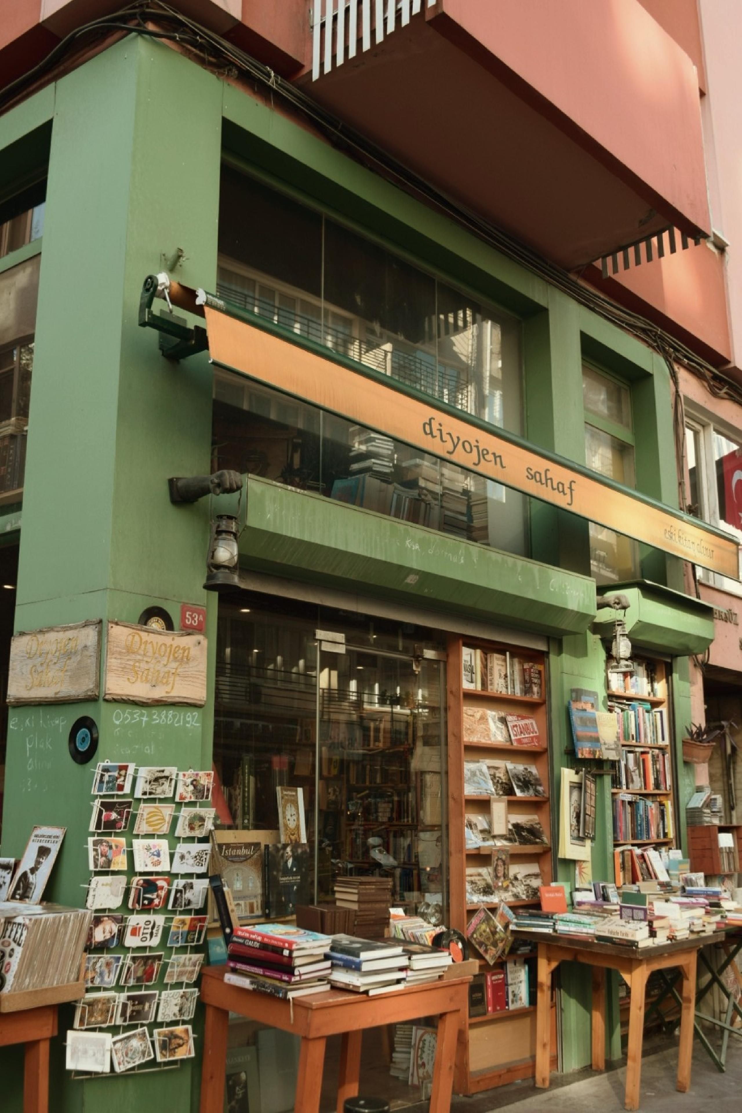 A quaint bookstore in Istanbul with books and postcards displayed outside on a sunny day.