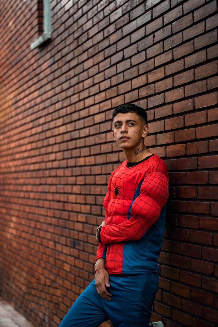 Man In Spiderman Costume Leaning On A Brick Wall