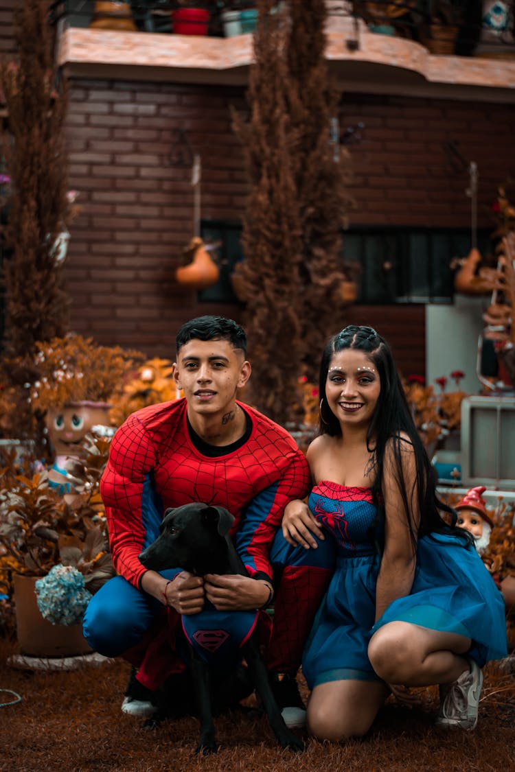 Couple Wearing Costumes Posing With Their Pet Dog