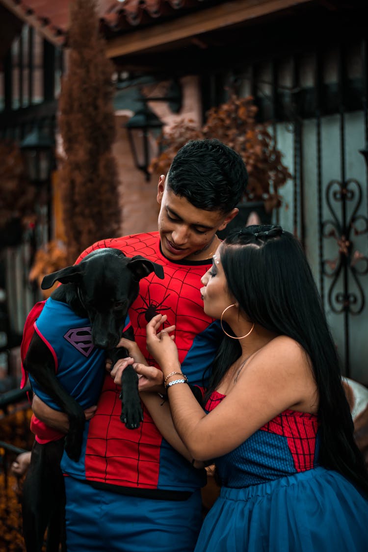 Man And A Woman Wearing Costumes With Their Pet Dog