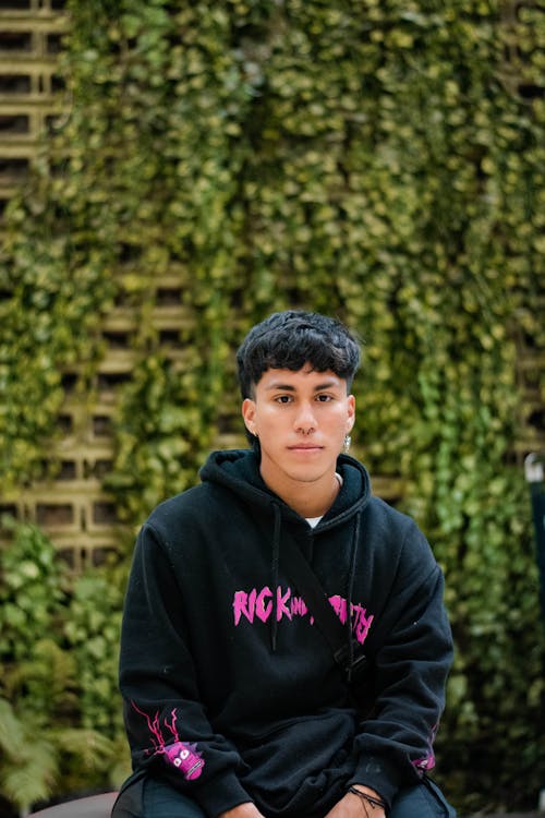 A Man in Black Sweater Sitting while Looking with a Serious Face