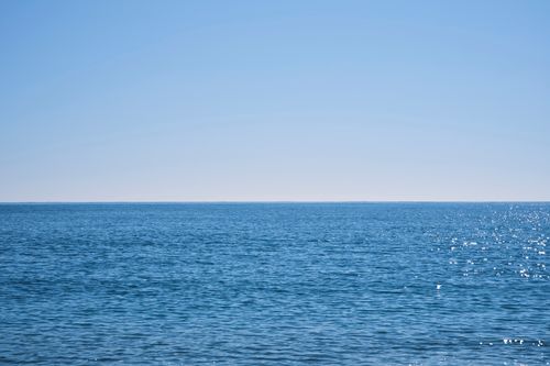Free Serene view of the endless ocean with a blue sky and gentle waves offering peaceful tranquility. Stock Photo