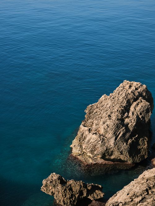 Free A stunning view of rock formations jutting from a serene blue ocean. Stock Photo