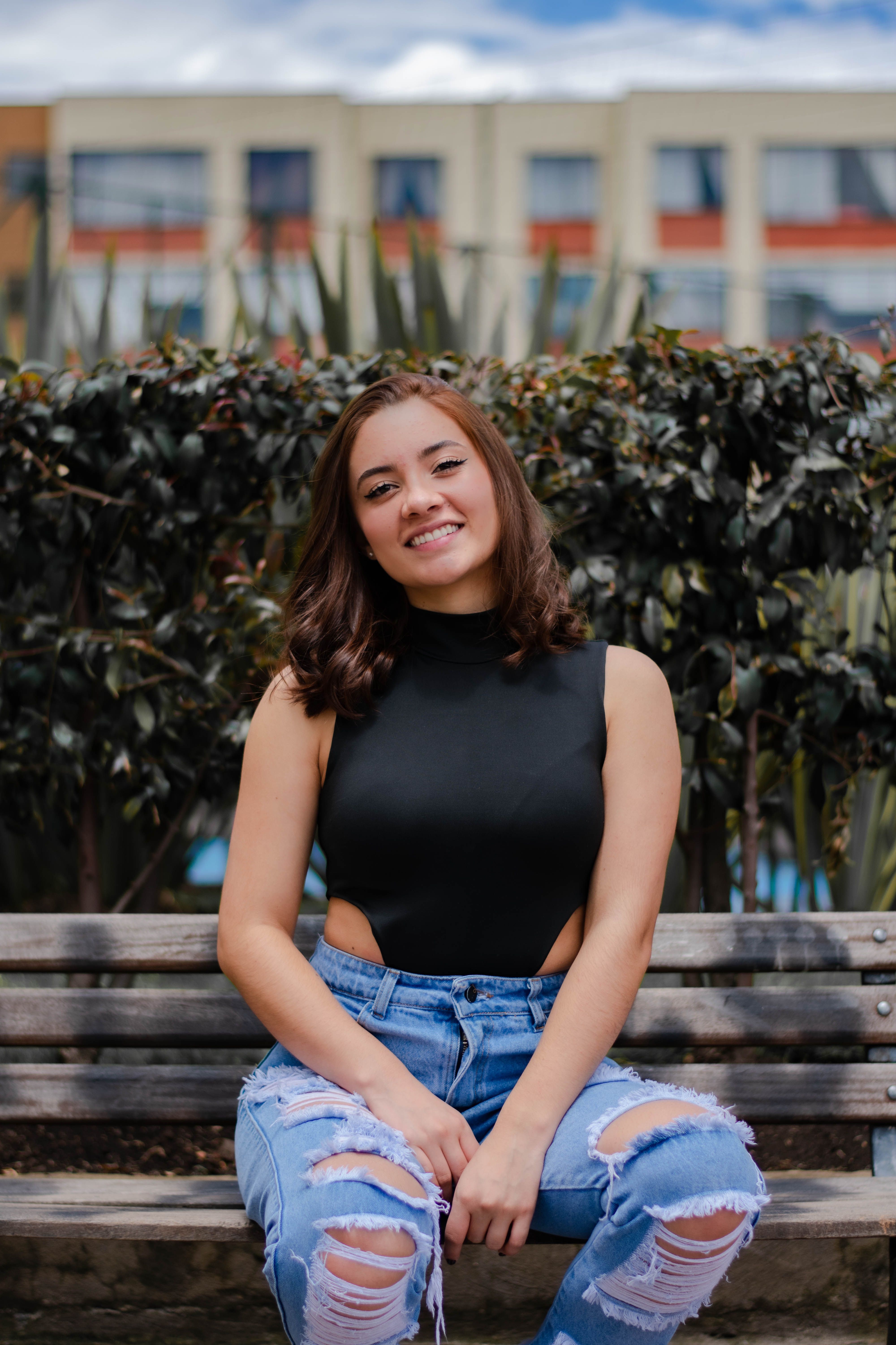Woman in Torn Jeans and Tank Top Sitting on the Bench · Free Stock Photo