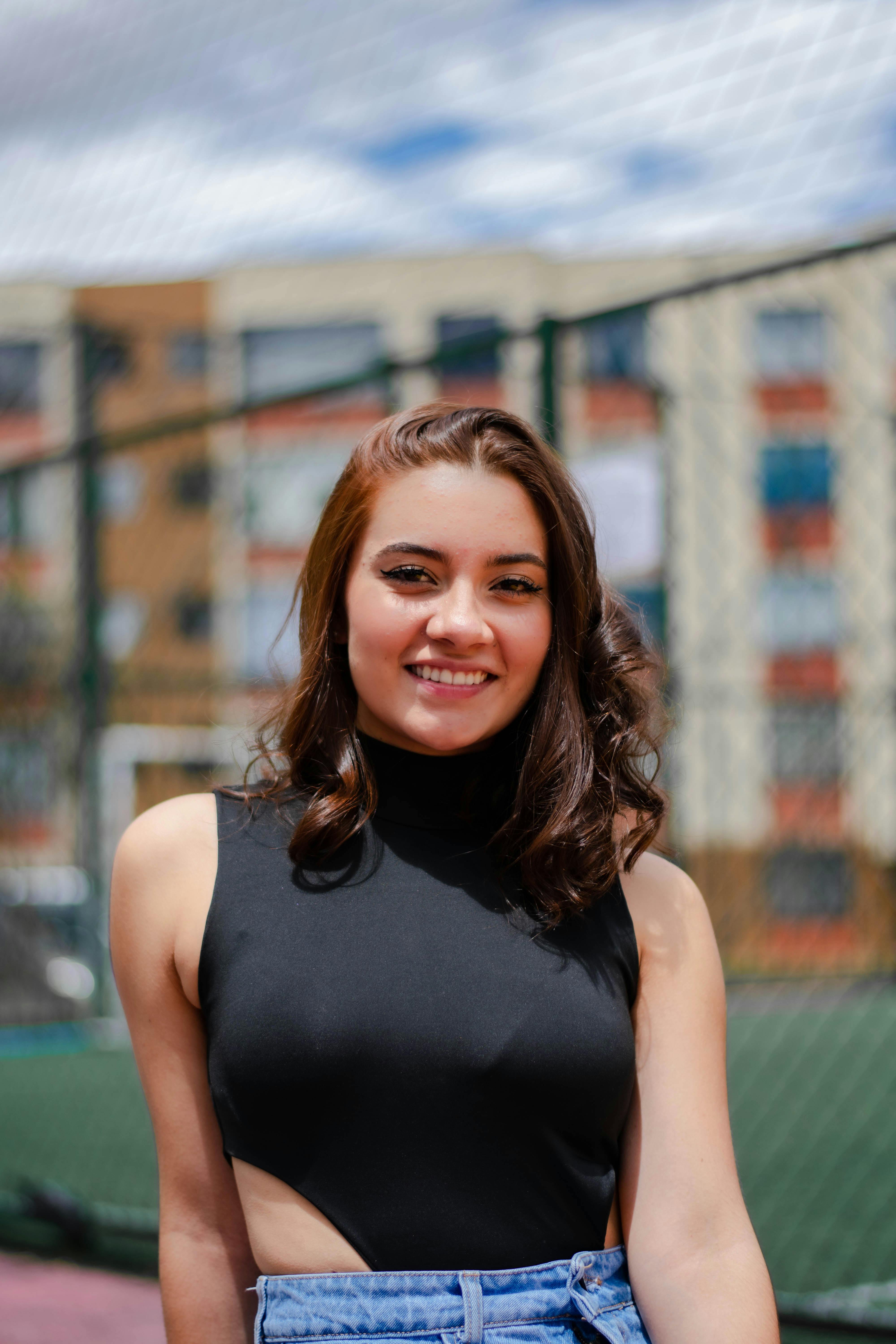 Portrait of a smiling young woman outdoors, capturing vibrant city vibes and modern fashion.