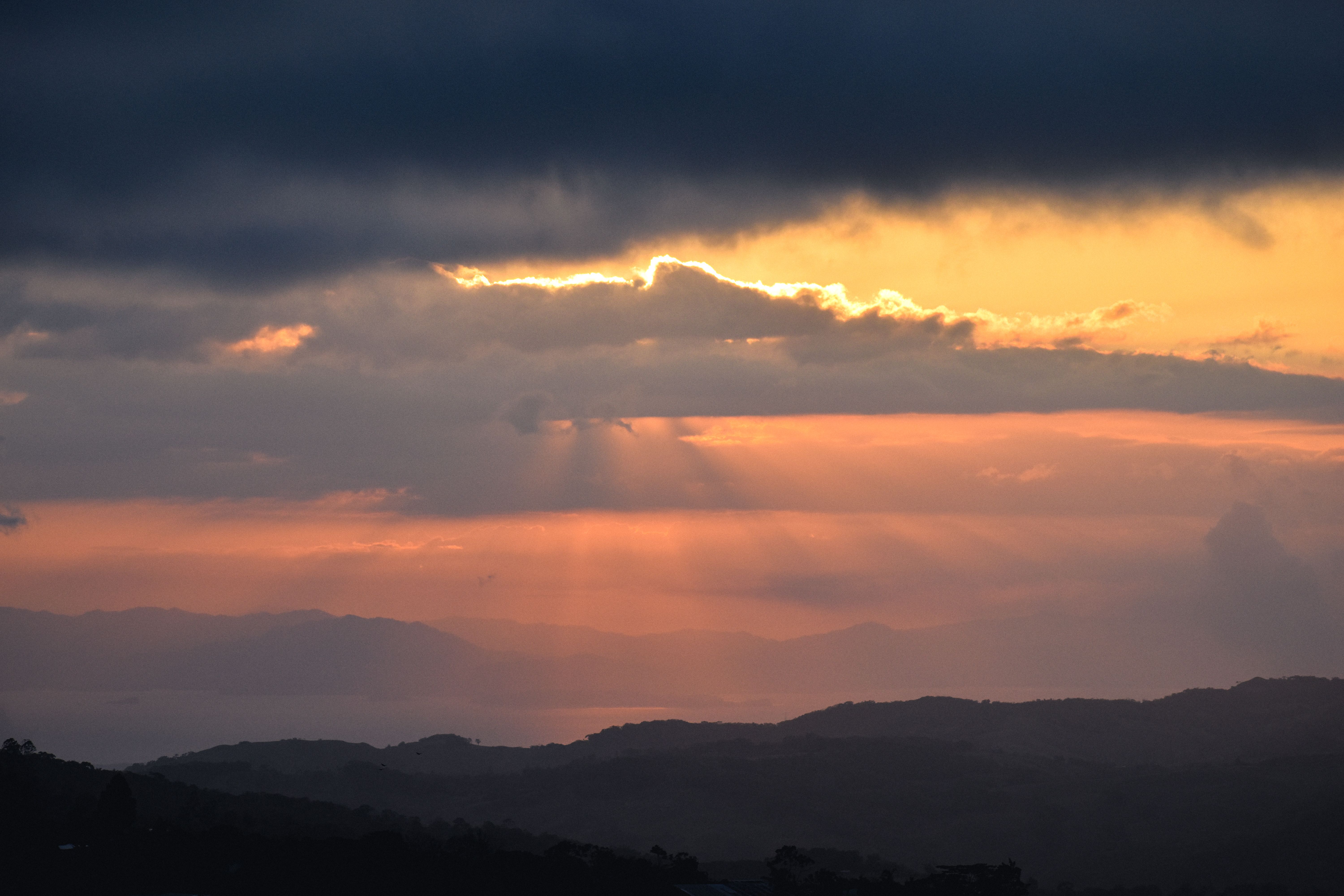 Stunning sunset in San Ramón, Costa Rica with vibrant clouds and hills.