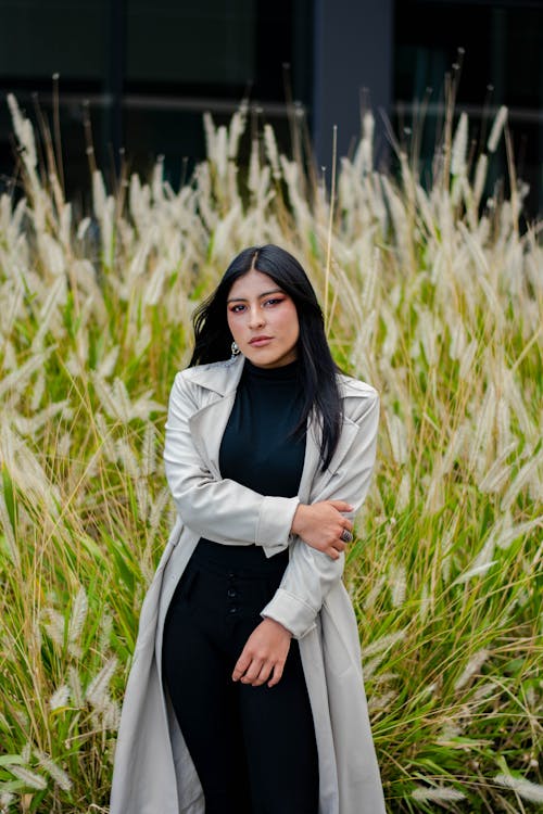 Photo of a Woman in a Gray Coat Standing Near Grass