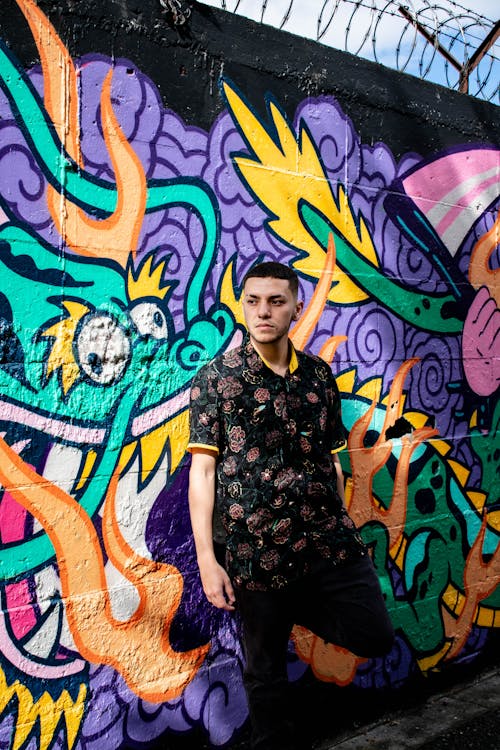 Free Man Wearing Floral Shirt Standing Beside a Graffiti Wall Stock Photo
