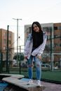 Woman in White Jacket and Blue Denim Jeans Standing Near Fence
