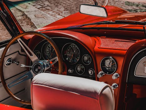 Close-up of a vintage convertible car interior with red dashboard and wooden steering wheel in Paris.