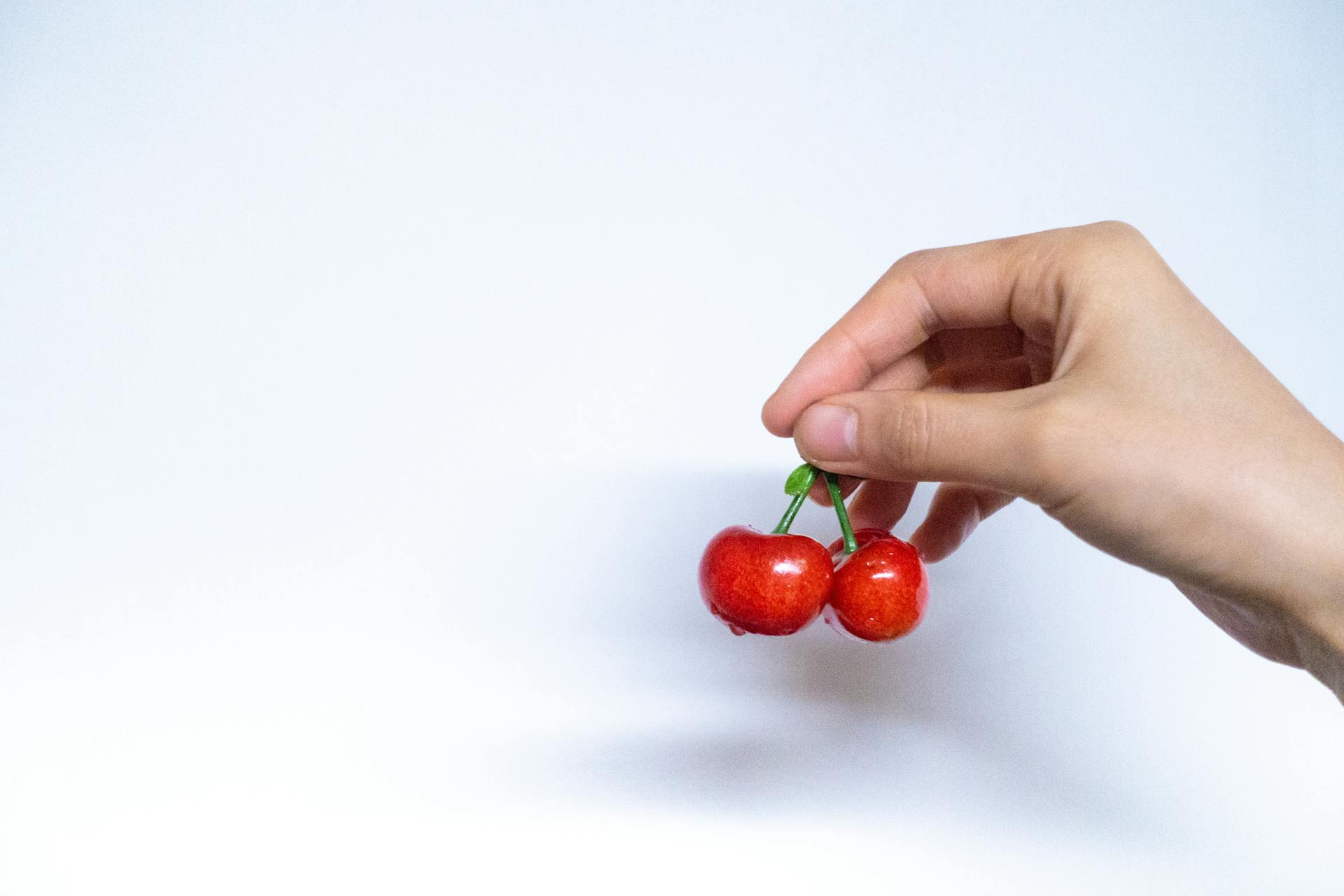 Person Holding Red Cherries