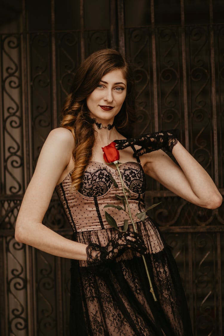 Woman In Vintage Lace Dress And Gloves Standing With Red Rose In Hand