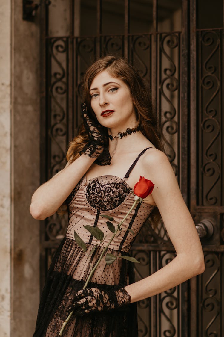 Redhead Woman Standing With Red Rose And Hand On Cheek