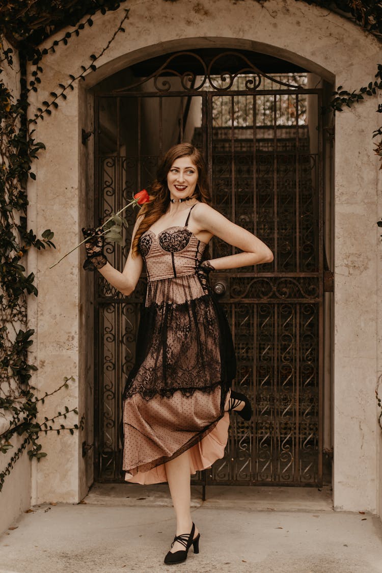 Smiling Woman Wearing Vintage Dress With Red Rose In Hand