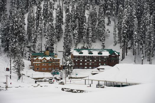 A picturesque view of snow-covered Hotel Hilltop in the serene winter landscape of Gulmarg, Kashmir.