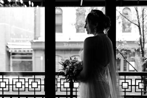 Grayscale Photo of Bride Holding Flowers 