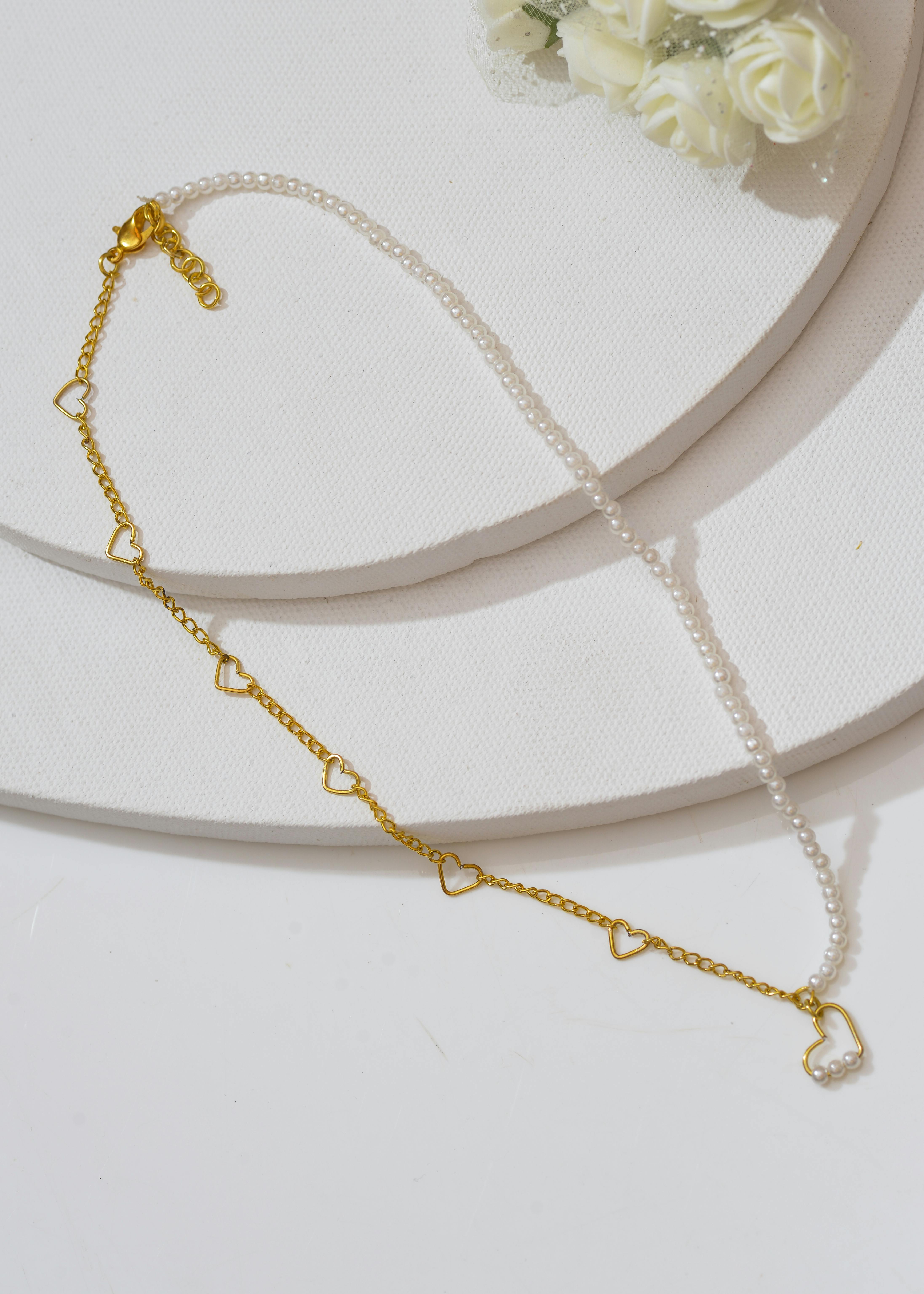 gold and pearl necklace on white surface