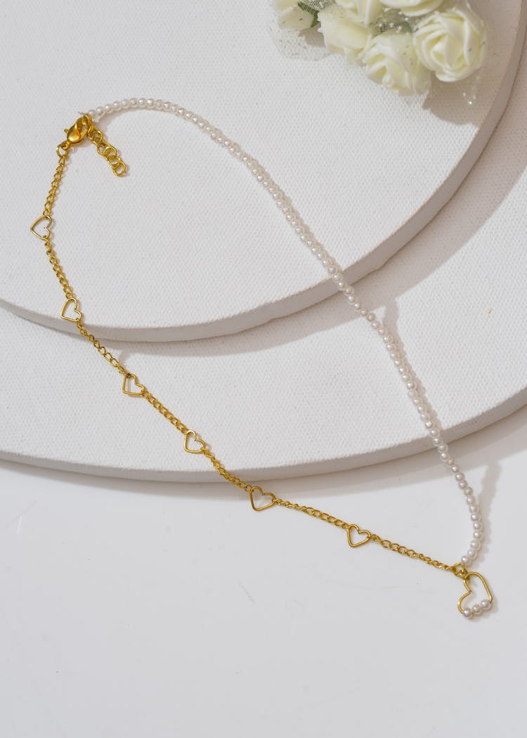 Gold And Pearl Necklace On White Surface