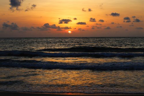 Free Dramatic sunset view with golden hues over ocean waves at the beach. Stock Photo
