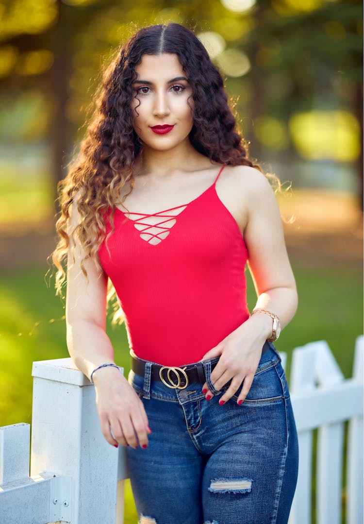 Woman In Red Top Leaning On White Fence