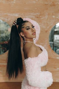 Portrait of a stylish woman with long black hair in a pink fur outfit in São Paulo.